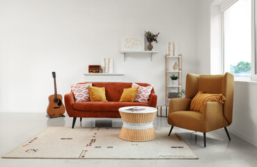 Cozy sofa with cushions and pictures in living room