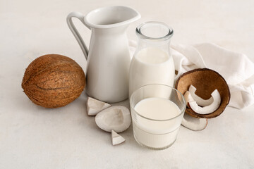 Jug, bottle and glass with tasty coconut milk on white background