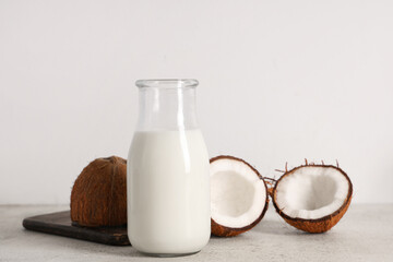 Bottle of tasty coconut milk on light background