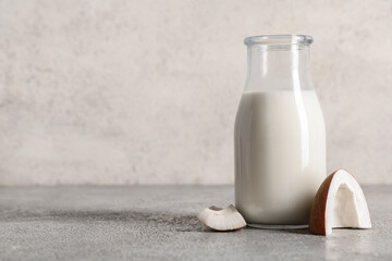 Bottle of tasty fresh coconut milk on grunge background, closeup