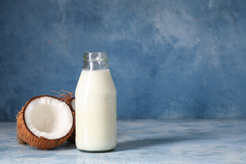 Bottle of tasty fresh coconut milk on blue grunge background