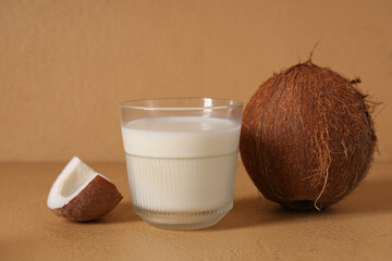 Glass of tasty fresh coconut milk on beige background, closeup