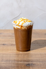 木のテーブルにプラスチックのコップにはいったキャラメルフラッペ