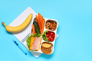 School supplies, lunch box with sandwich and banana on blue background. Top view © Pixel-Shot