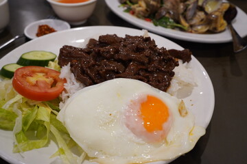 vietnamese shaking beef with tomato, sunny-side egg, cucumbers, and rice - bo luc lac. 