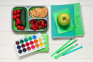 School supplies, lunch box with berries and cookies on white wooden background. Top view