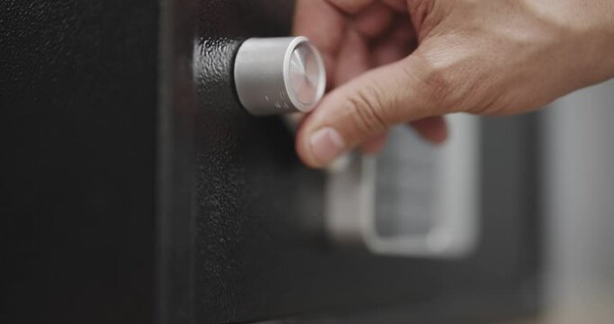 Thief opens a black safe with a silver keypad, digital display and a silver lock on robbery crime action
