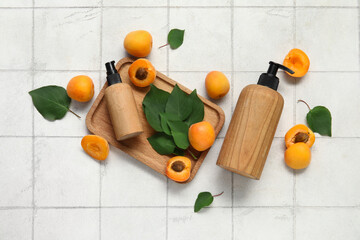 Bottles of cosmetic products with fresh apricots on white tile background