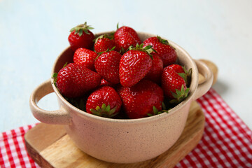 Bowl with fresh sweet strawberries on light blue background