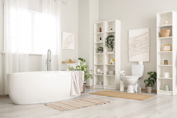 Interior of bathroom with toilet bowl, bathtub and shelving unit