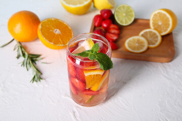 Glass of fresh infused water with strawberries and different citrus fruits on white table