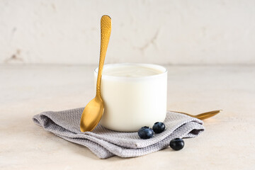 Glass of tasty yogurt with blueberries on white background
