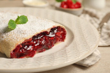 Delicious strudel with cherries, powdered sugar and mint on white wooden table, closeup