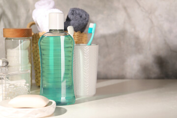 Bottle of mouthwash, toothbrushes and soap on light table in bathroom, space for text