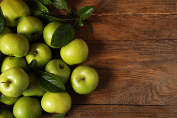 Ripe green apples with leaves on wooden table, flat lay. Space for text