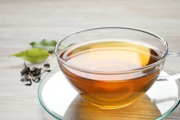 Refreshing green tea in cup on light wooden table, closeup