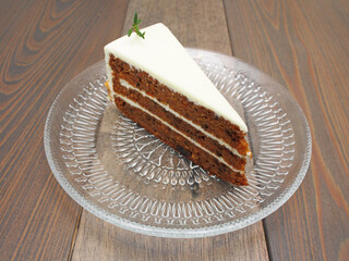 Slice of chocolate carrot cake on a glass plate on  wooden table   