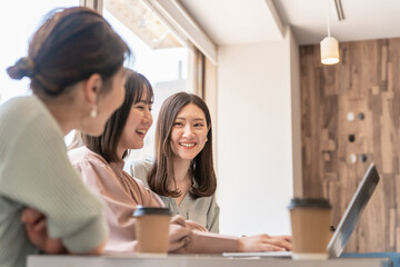 Fototapeta premium カフェ・会社・オフィスで会議・打ち合わせ・ミーティングをするアジア人女性（楽しい・笑顔） 