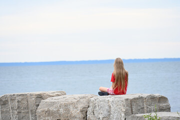 blonde girl sits and looks at the sea