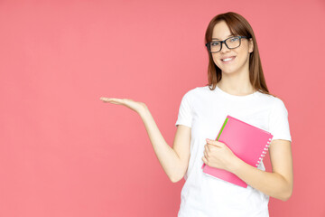 Fototapeta premium An attractive, young girl in glasses and books in her hands