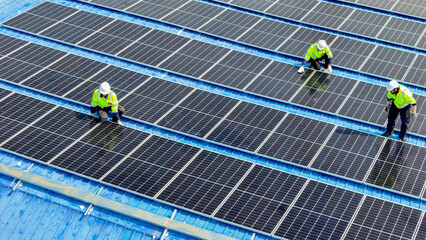 engineer man inspects construction of solar cell panel or photovoltaic cell by electronic device. Industrial Renewable energy of green power. factory worker working on tower roof.