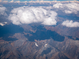 View From the Airplane of the Rocky Mountains Over Peru with a Blue Sky and Clouds as a Background
