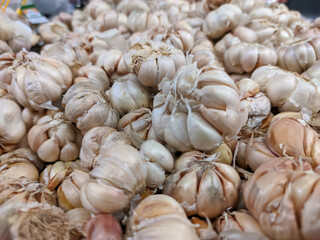 A close-up of a stack of garlic bulbs reveals their papery white skins and compact, segmented cloves.