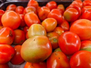 A close-up bright red tomatoes reveals their juicy, plump perfection. Each tomato's smooth, glossy skin captures the light, emphasizing their vibrant color and freshness.