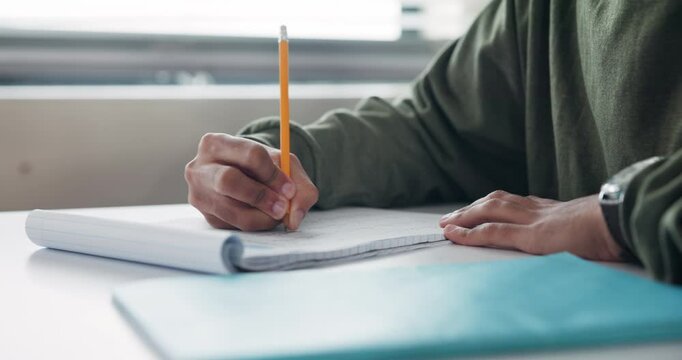 Education, hands and writing with student at desk in classroom of school for assessment, exam or test. Development, learning and study with person in class for knowledge, notes or scholarship