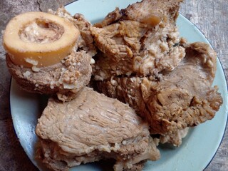 Beef that has been cooked after being boiled is placed on a plate on the cement floor.