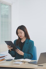 Asian professional businesswoman working on tablet computer in a corporate office