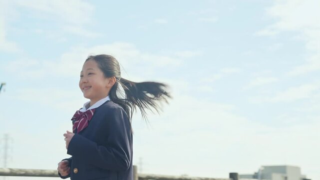 青空の下を走る制服を着た女の子