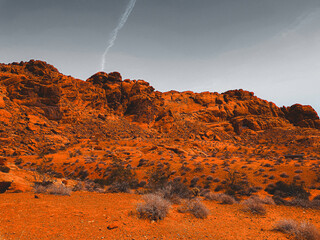 a rugged red rock formation in a desert landscape, with a clear sky providing a stark contrast to...