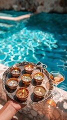 Fototapeta premium Celebrating Navaratri by the Pool Close-Up of Hand Holding Diya Tray with Sunglasses, Cocktail Glasses, and Serene Blue Water