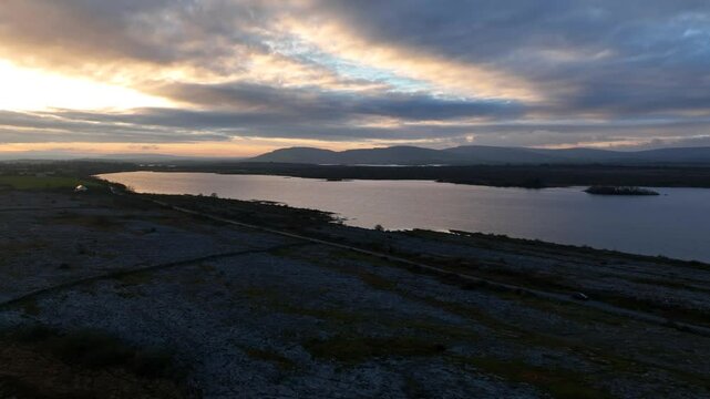 Lough Bunny, County Clare, Ireland, November 2023. Drone dolly along lake shore and road cutting across the Burren at sunset.