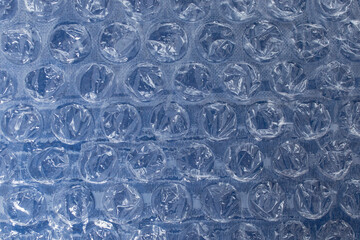 Bubble wrap plastic foil over deep blue background, flat lay close up abstract textured backdrop