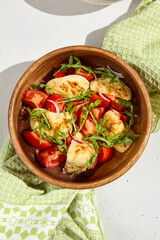 Grilled Halloumi Cheese with Tomatoes and Arugula in a Wooden Bowl
