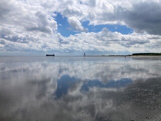 Eindrücke aus dem niedersächsischen Wattenmeer der Nordsee vor Cuxhaven mit Blick auf die Kugelbarke bei blauem Himmel mit Wolken und Spiegelung