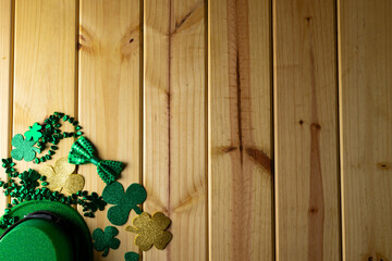 Image of green hat, clover and copy space on wooden background © vectorfusionart