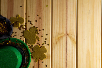 Image of green hat, clover and copy space on wooden background © vectorfusionart