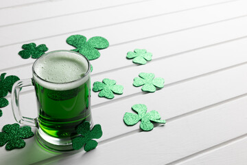 Image of glass with green beer, clover and copy space on white wooden background © vectorfusionart