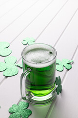 Image of glass with green beer, clover and copy space on white wooden background © vectorfusionart