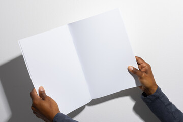 Hands of an African American man holding an open blank magazine, with copy space