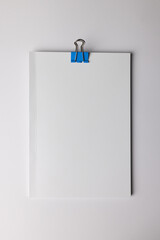 Naklejka premium A blank white paper held by a blue binder clip, with copy space