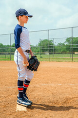 Obraz premium Youth male baseball player on the pitchers mound, ready to pitch a fastball