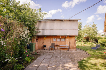Valmiera, Latvia - July - 5, 2024 - A rustic backyard with a wooden shed, garden area, patio...