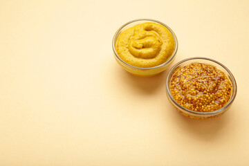 Dijon mustard with french mustard on beige background. Space for text