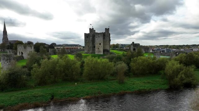 Trim Castle, County Meath, Ireland, October 2023. Drone orbit counter clockwise above River Boyne with reflections of Medieval historic tower buildings shimmering in water below ancient Stronghold.