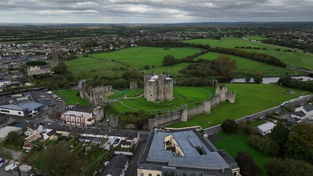Trim Castle, County Meath, Ireland, October 2023. Drone orbits counter clockwise while descending towards the historic Medieval Fortress pushing towards the imposing defensive curtain walls.