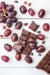 Box of chocolate and bunch of grapes are on table
